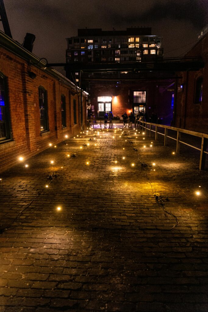 A rustic brick alley illuminated by warm string lights on a tranquil night.